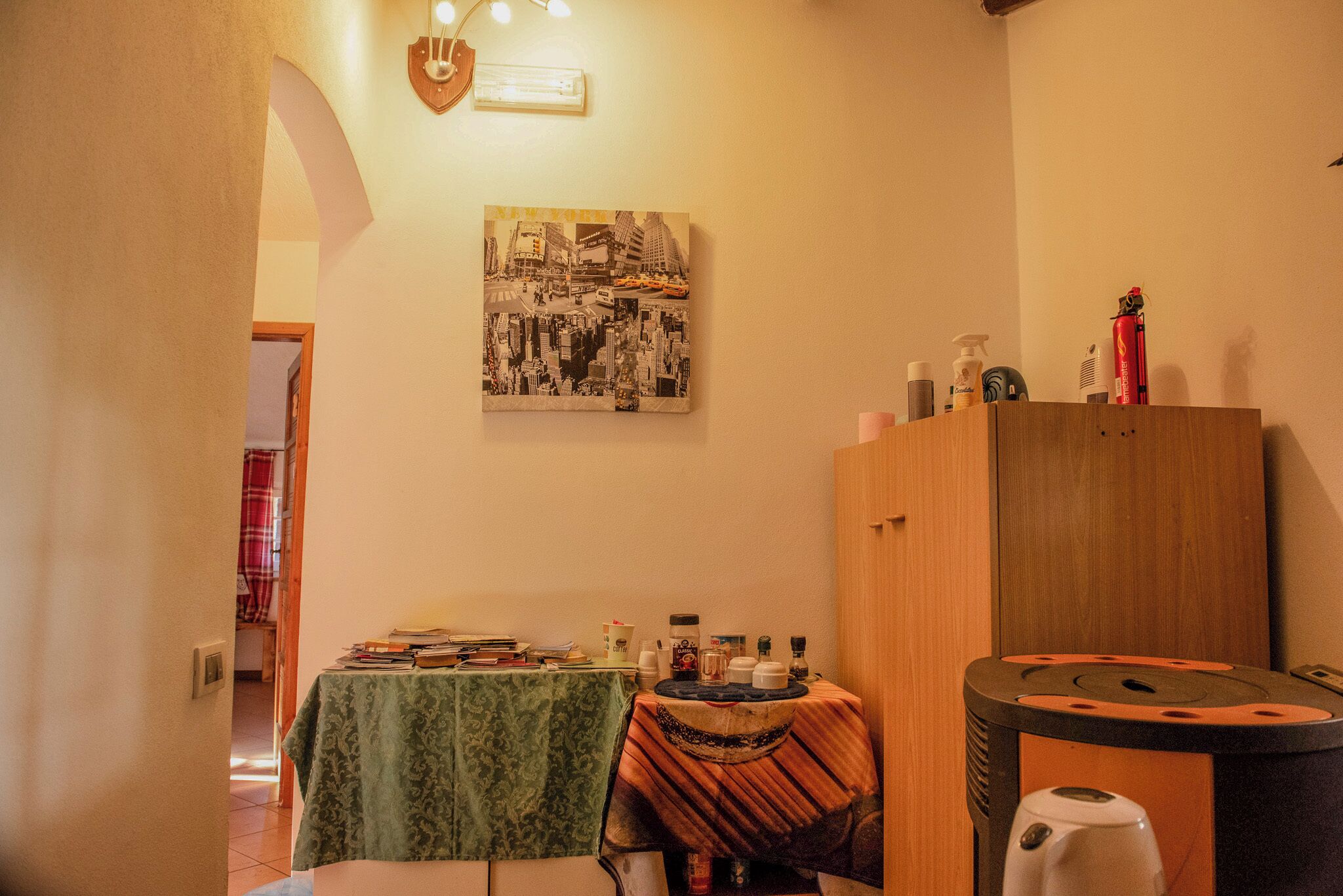 Una stanza con un tavolo ricoperto da una tovaglia verde, un armadietto in legno e un quadro appeso al muro raffigurante un panorama urbano.