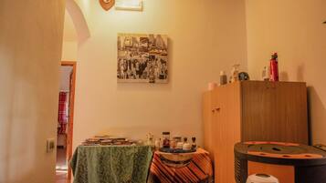 Una stanza con un tavolo ricoperto da una tovaglia verde, un armadietto in legno e un quadro appeso al muro raffigurante un panorama urbano.
