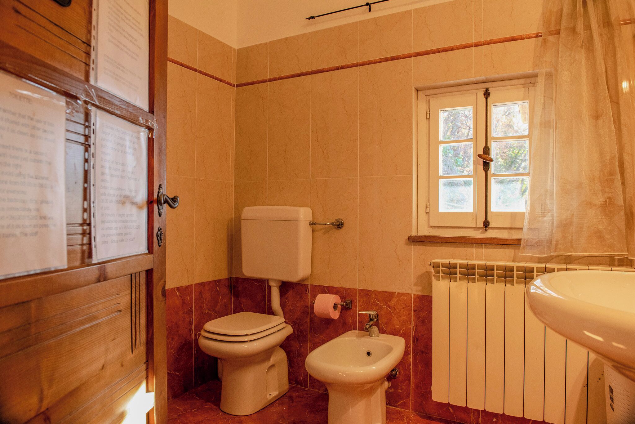 A bathroom with a toilet, bidet, and radiator.