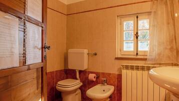 A bathroom with a toilet, bidet, and radiator.