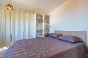 Un dormitorio con cama, armario y lámpara colgante.