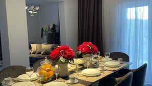 A modern dining room with a long table set for a meal, featuring a vase with red flowers, a fruit bowl, and a chandelier. - Charming Holiday home with private pool,teniss field WiFi... Imotski,Croatia (Gornji Vinjani)
