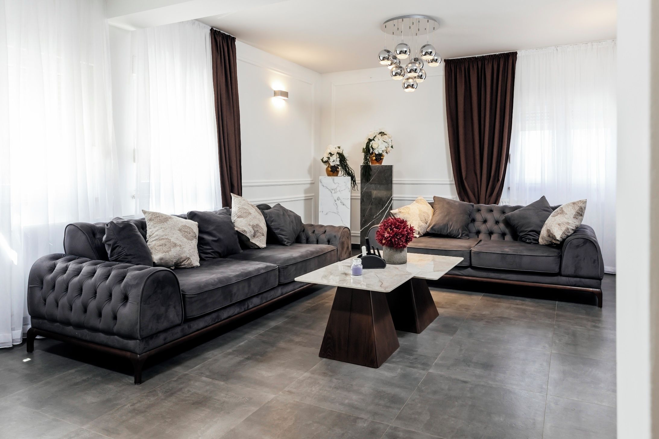 Un salon moderne avec deux canapés gris, une table basse en marbre et un vase décoratif.