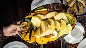 Un plateau de fruits coupés en tranches, notamment de la mangue, de l’ananas et de la fruit de la passion.