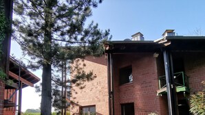 A brick building with a covered outdoor area, a large tree, and a clear sky. - Spacious, family-friendly vacation apartment in architect's house with garden (Lauf)