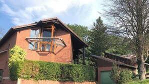 A brick building with a sloped roof, large windows, and a covered porch area. - Spacious, family-friendly vacation apartment in architect's house with garden (Lauf)