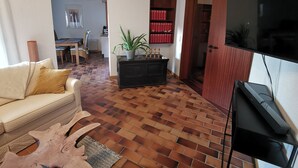 A living room with a sofa, a television, a bookshelf, and a patterned rug. - Spacious, family-friendly vacation apartment in architect's house with garden (Lauf)