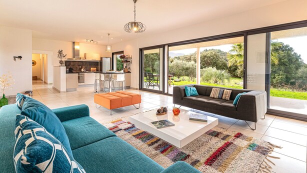 Ein modernes Wohnzimmer mit Sofa, Couchtisch und Blick ins Freie.