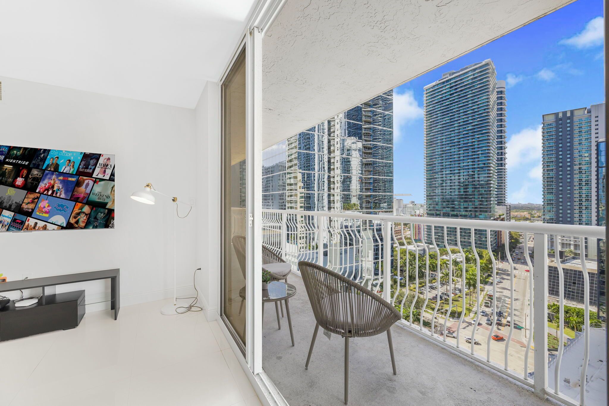 A balcony with a city view, a wall-mounted photo collage, and a small seating area.