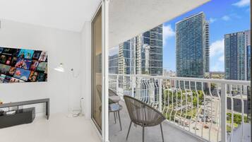 A balcony with a city view, a wall-mounted photo collage, and a small seating area.