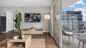 A modern living room with a large window, a sofa, a coffee table, and a plant. - Chic Brickell Condos – Prime Location (Miami)