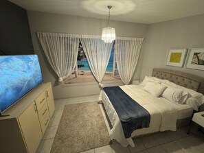 Relax in this serene bedroom with a large bed, TV, and bedside table.