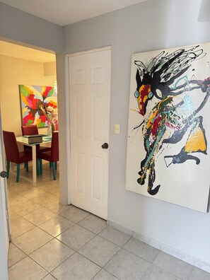 Enter a beautifully appointed hallway leading to a dining area with a traditional door and vibrant artwork.