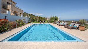 A rectangular swimming pool with a clear blue water surface, surrounded by lounge chairs and a stone building with arches. - Arios Lux villa,50 sqm pool,Rural,8 guests,Rethymno (Agia Paraskevi)
