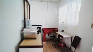 A small, compact kitchen with basic appliances, a dining area with a table and chairs, and a window with curtains.