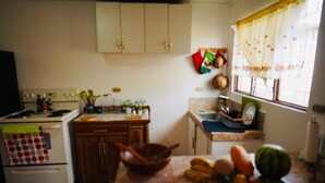 A kitchen with a stove, sink, and various kitchen items on the counter.