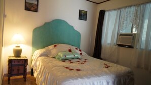 A neatly made bed with a teal headboard, a bedside lamp, and a small wooden nightstand.