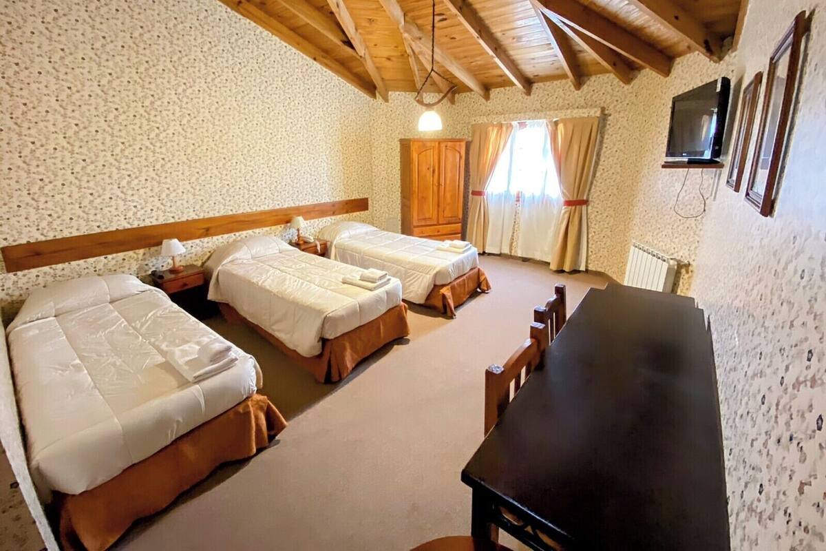 A room with two beds, a wooden table, and a TV.