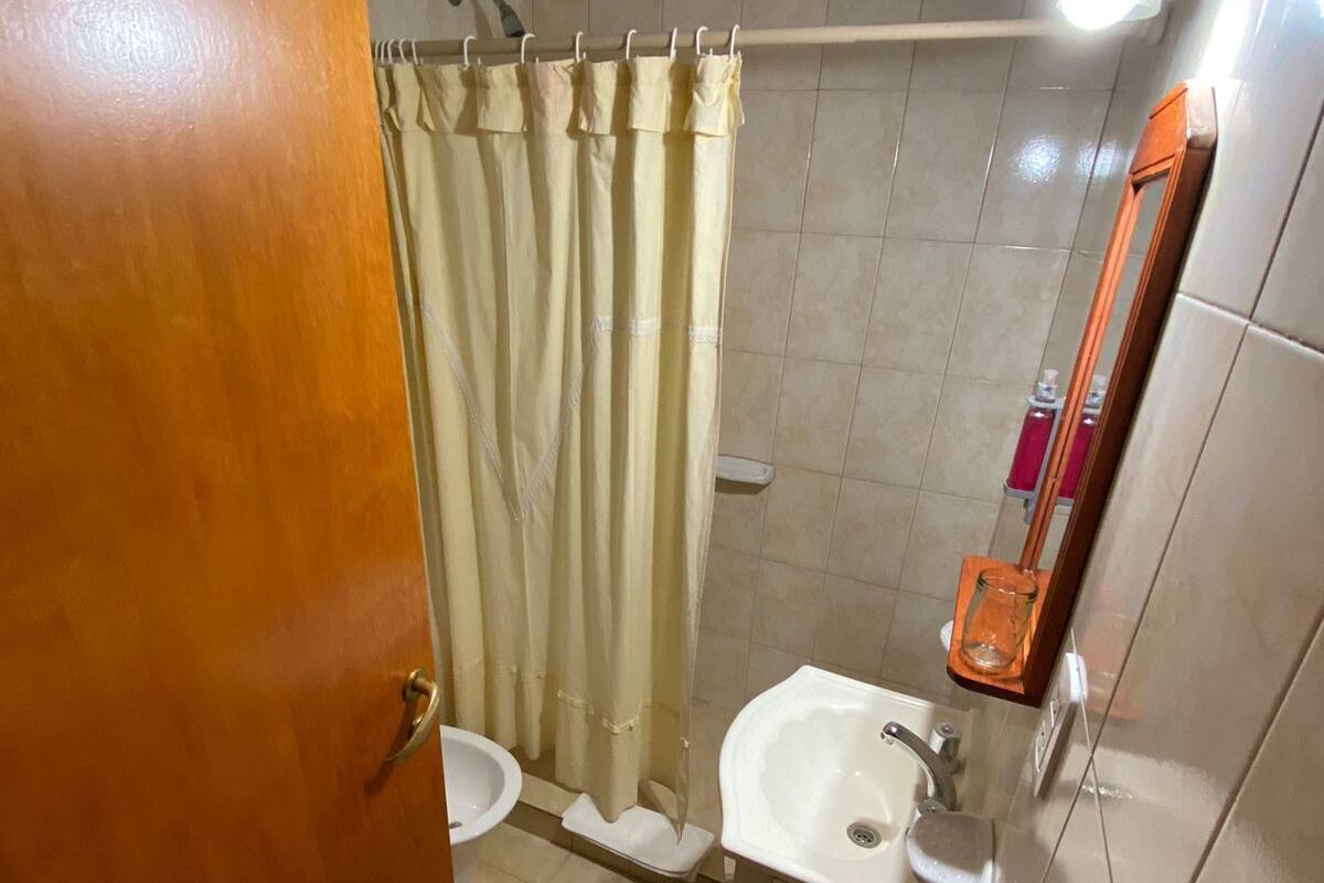 A bathroom with a toilet, bidet, sink, and a shower curtain.