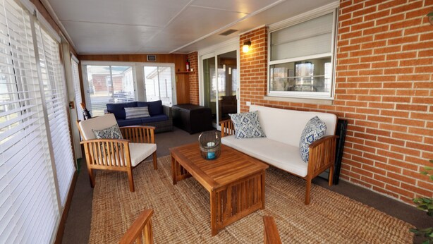 A cozy living area with a brick wall, wooden furniture, and a large window. - Timo's Place (Wilmington)