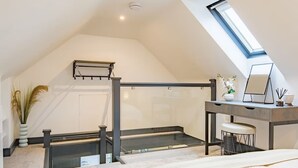 Un dormitorio con techo inclinado, un escritorio con silla, una cama, una ventana y una planta.