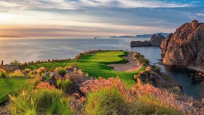 A coastal golf course with a view of the sea and rocky cliffs.