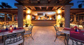 An outdoor dining area with tables and chairs, a central bar, and potted plants. - 2 bed, 3 bath, full kitchen, in-room laundry, balcony at tranquil golf resort  (Ensenada Blanca)