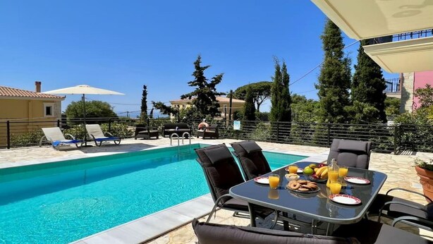 Un espace aménagé au bord de la piscine, avec des chaises longues, une table où sont servis les articles du petit-déjeuner et une vue dégagée sur la piscine.