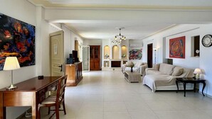 Un salon spacieux avec une cheminée, un coin repas avec une table et des chaises en bois, et un espace détente avec un canapé et des fauteuils.