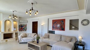 Un salon moderne avec une cheminée, deux canapés, une table basse et un grand tableau abstrait.
