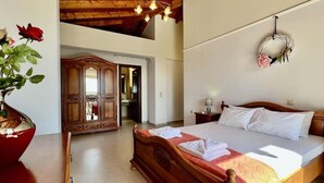 Une chambre spacieuse avec un grand lit, un plafond en bois et un miroir au mur.