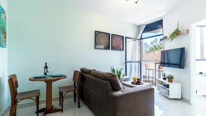 A modern living room with a sofa, dining table, chairs, a TV, and a city view through large windows. - Piscina - Ibirapuera - Brazillian Corner (São Paulo)