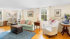 A living room with a sofa, armchair, and a table with a vase of flowers. - Beauchamp Cottage, near Rockport Harbor and golf c (Rockport)