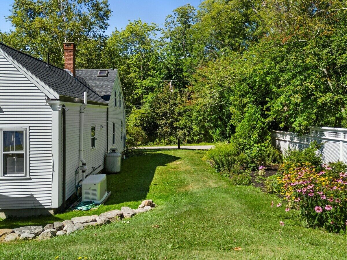 A residential property with a house, a lawn, and a garden with flowers.