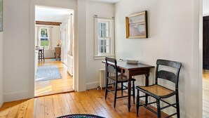 A dining area with a wooden table, two chairs, a window, and a radiator. - Beauchamp Cottage, near Rockport Harbor and golf c (Rockport)