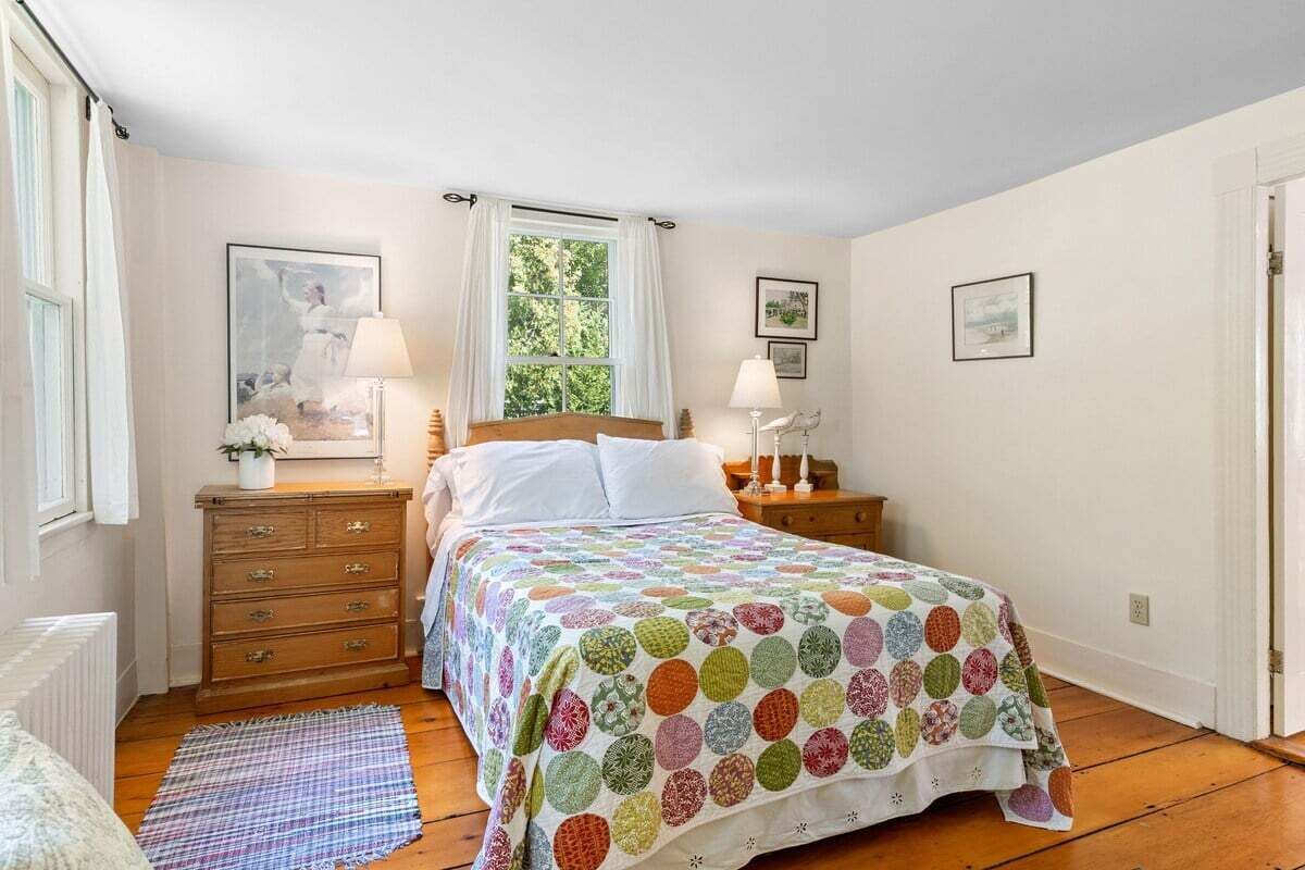 A bedroom with a bed, a dresser, a nightstand, a window, and a door.