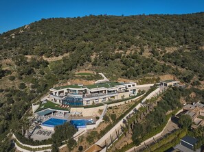 Uma villa moderna com piscina, vários espaços de estar ao ar livre e vista para uma paisagem montanhosa.