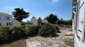 A paved pathway leading to a white building with a tiled roof, surrounded by greenery and a clear blue sky. - Family home 300m from the beach  (Saint-Jean-de-Monts)