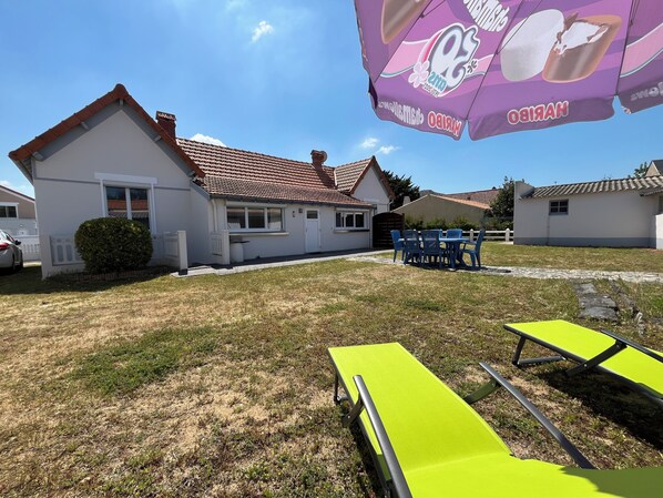 Een huis met een pannendak, een kleine tuin en tuinmeubilair.