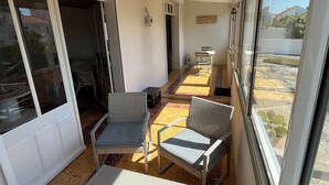 A sunlit room with a white table, two wicker chairs, a sofa, and a view of the outside through large windows. - Family home 300m from the beach  (Saint-Jean-de-Monts)