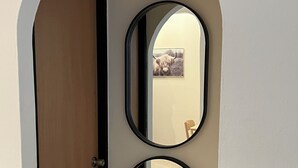 Een deur met twee spiegels aan weerszijden, een lijst met foto aan de muur, en een houten deurpost.