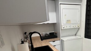 Een kleine keuken met een houten aanrecht, een zwart spoelgedeelte en een inbouwoven.