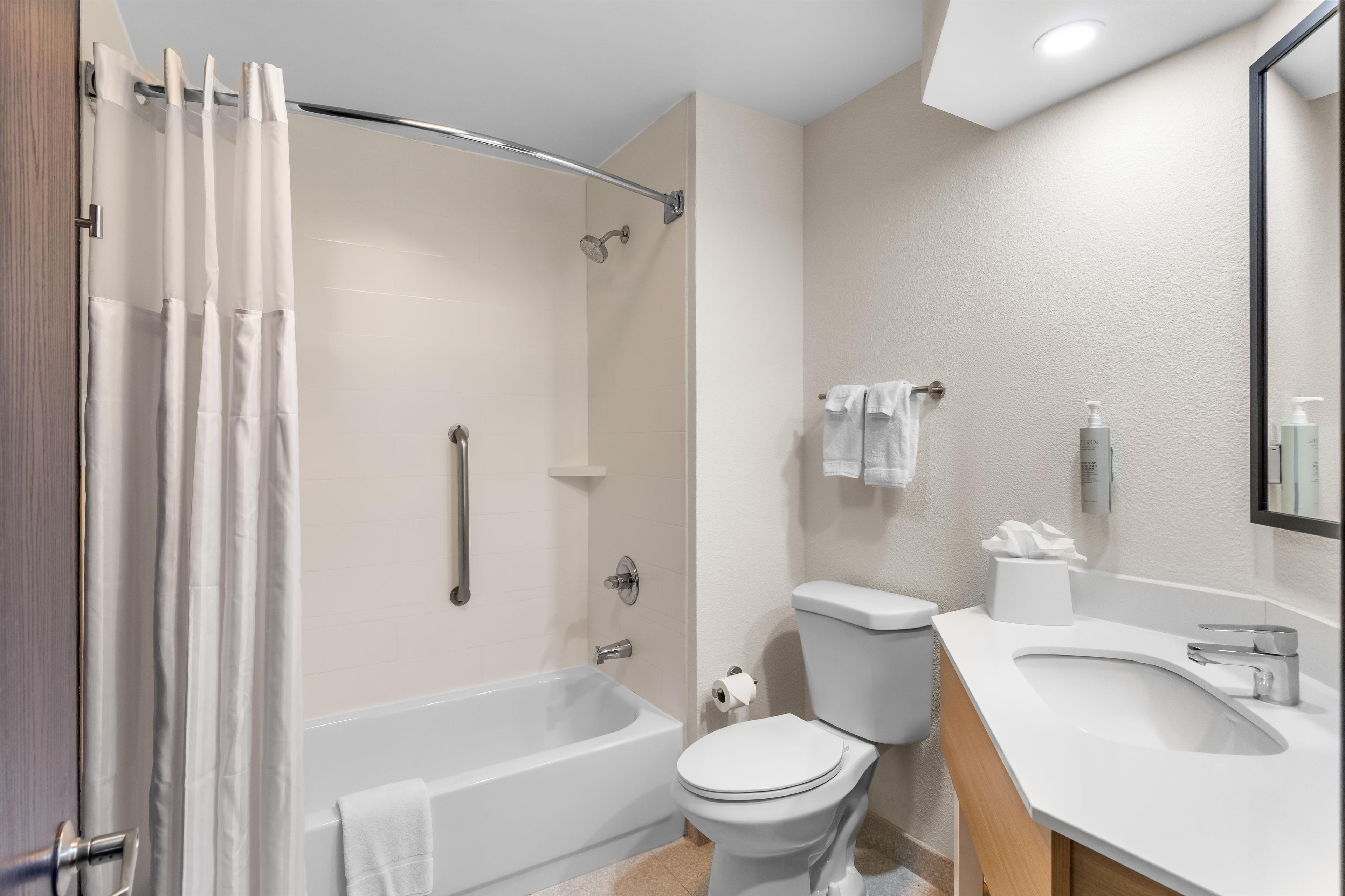 A modern bathroom with a bathtub, toilet, and shower.