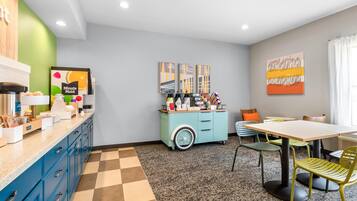 Uma cozinha moderna com espaço para café, área de refeições com mesa e cadeiras, e obras de arte nas paredes.