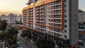 A multi-story residential building with balconies, a parking garage below, and a cityscape in the background. - Studio AD330 Alto da Boa Vista (São Paulo)