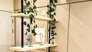 A bedroom with a bed, a bedside table with a remote control, books, a wall-mounted shelf with decorative items, and an air conditioner. - Studio AD330 Alto da Boa Vista (São Paulo)