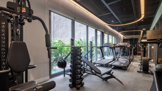 A modern gym with various exercise equipment, large windows, and a view of greenery outside. - Studio AD330 Alto da Boa Vista (São Paulo)