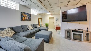 A modern living room with a sectional sofa, a flat-screen TV, and a fireplace. - 1 Mi to Dtwn: Cozy Retreat in New Kensington! (New Kensington)