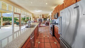 A spacious kitchen with a large island, stainless steel appliances, and a view of the outdoors.