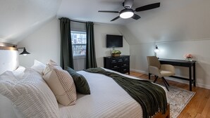 Une chambre à coucher comprenant un lit, un bureau, une chaise et un ventilateur de plafond.